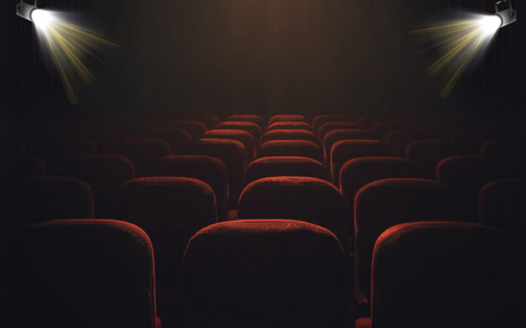 A dark image of red cinema chairs with two spotlights.