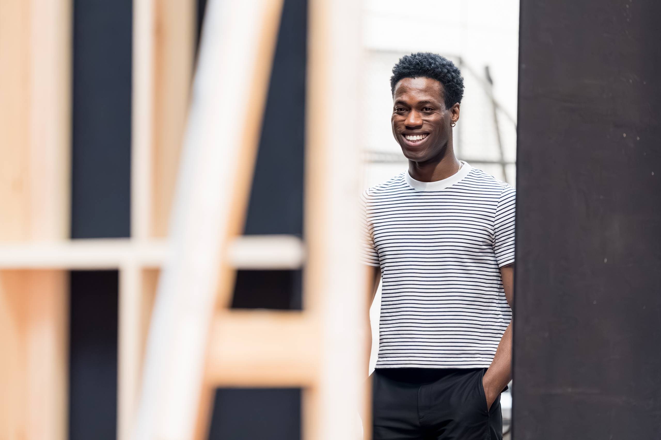An actor stands smiling in a backstage area.