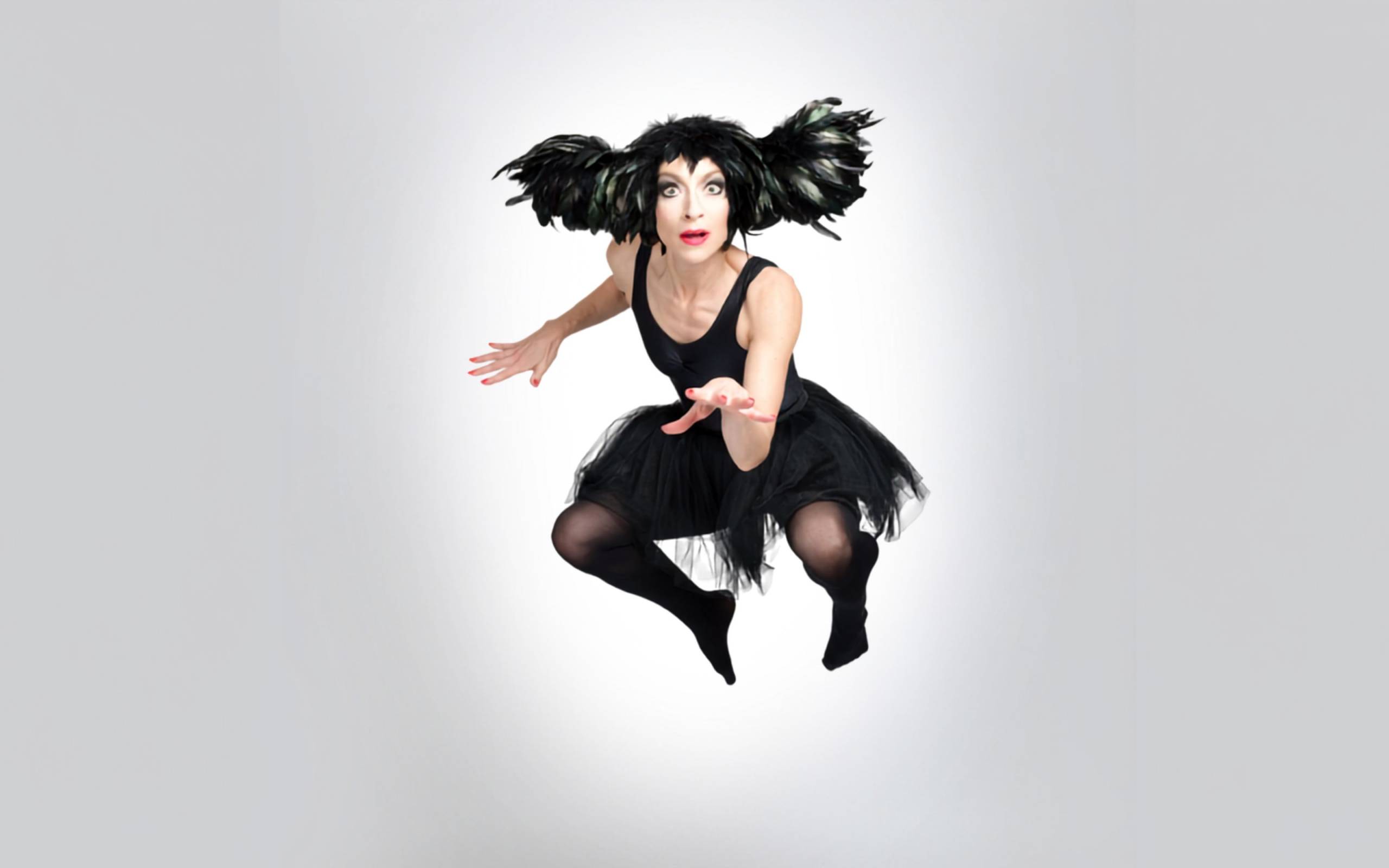 An Evening Without Kate Bush show artwork. A woman in a black dress, with black feathers in her hair, is jumping in the air.